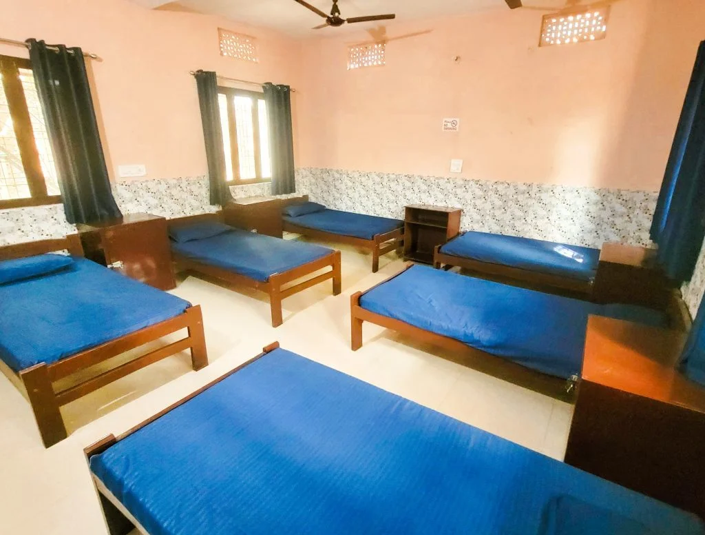 Cozy comfort within the dorm rooms: Step inside the inviting dorm rooms at Sage House Yoga's retreat center, where a warm and comfortable ambiance welcomes guests. From the inside, guests can enjoy a pleasant view of the room's serene decor, comfortable beds, and personal spaces, providing a cozy retreat during their stay.