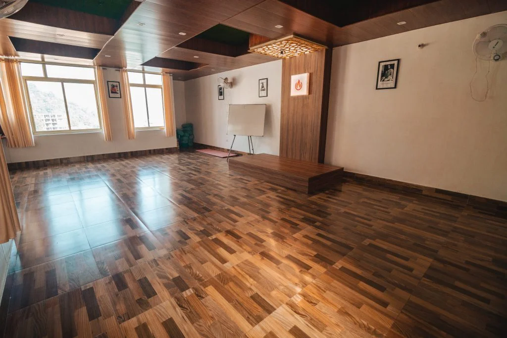 Tranquil Yoga Hall at Sage House Yoga, Rishikesh: A serene space adorned with natural light, yoga mats, and soothing ambiance, inviting practitioners to embark on a transformative yogic journey.