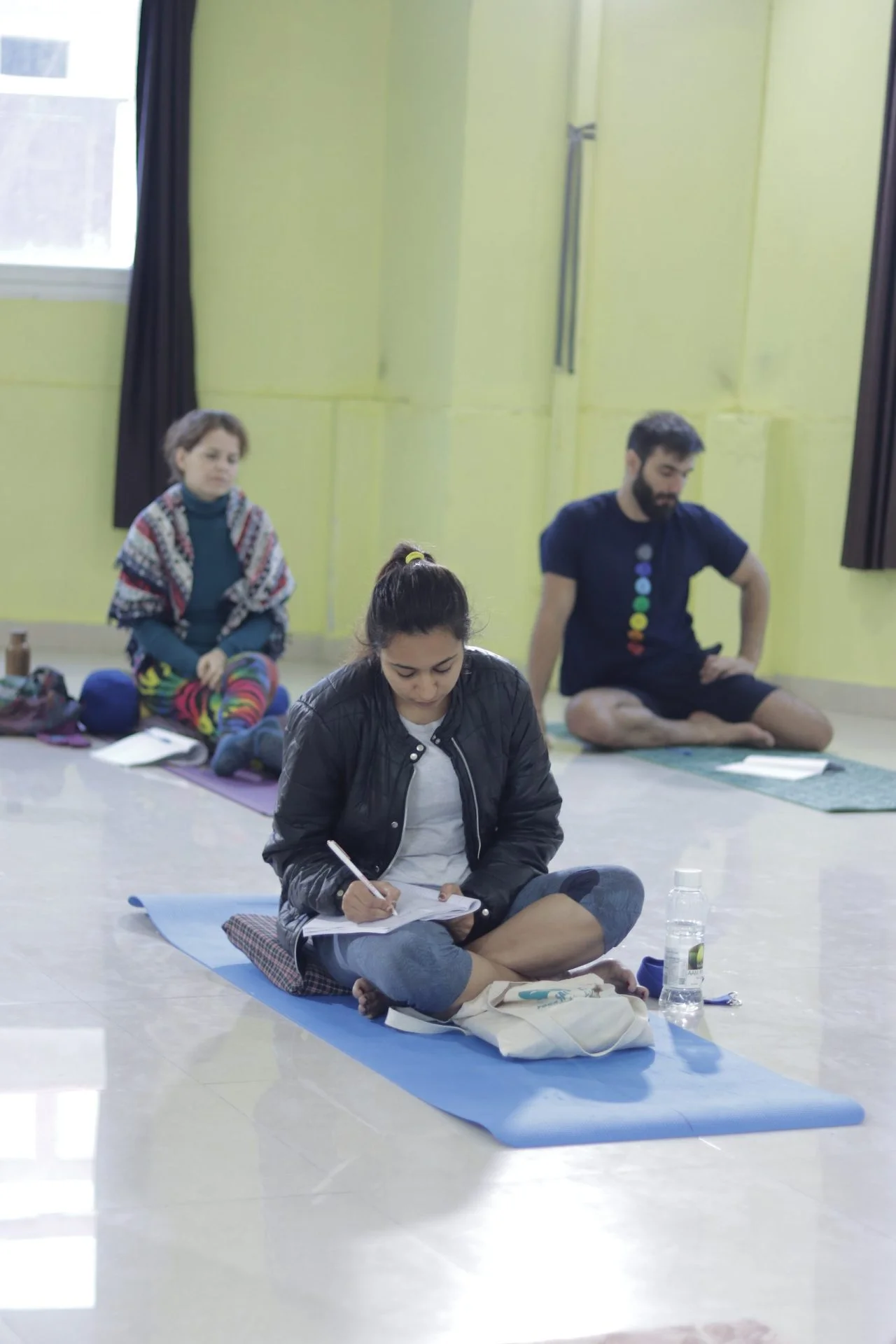 Knowledge absorption at Sage House Yoga: Engaged students diligently take notes of the insightful class lecture, fostering a deeper understanding of yoga philosophy and principles.